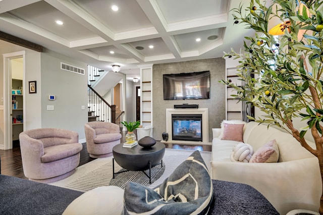 living room featuring coffered ceiling, beamed ceiling, crown molding, hardwood / wood-style flooring, and a tiled fireplace