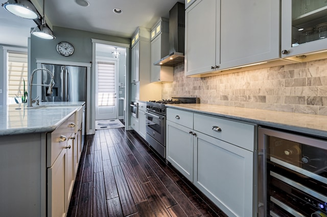 kitchen with wine cooler, wall chimney exhaust hood, stainless steel appliances, light stone countertops, and white cabinets