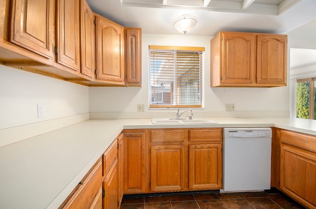 kitchen featuring dark tile patterned floors, dishwasher, light countertops, and a sink