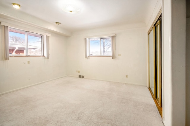 unfurnished bedroom featuring a closet, multiple windows, carpet, and visible vents