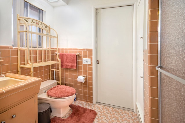 bathroom with a wainscoted wall, toilet, tile walls, and vanity