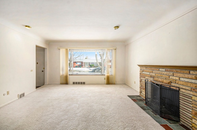 living area with baseboards, visible vents, a stone fireplace, and carpet