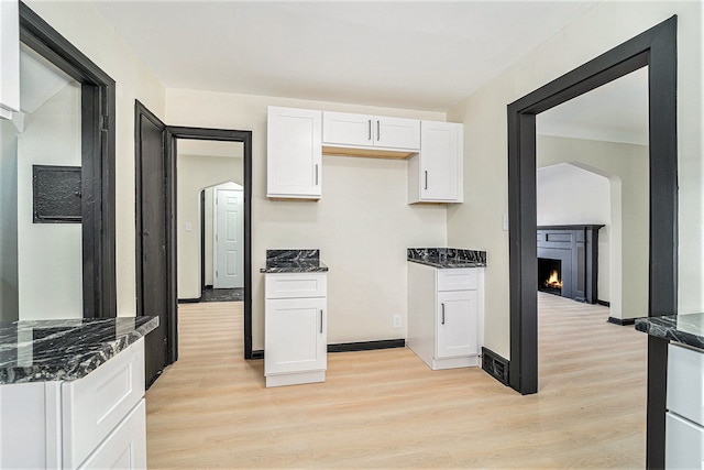 kitchen with dark stone countertops, light hardwood / wood-style floors, and white cabinets