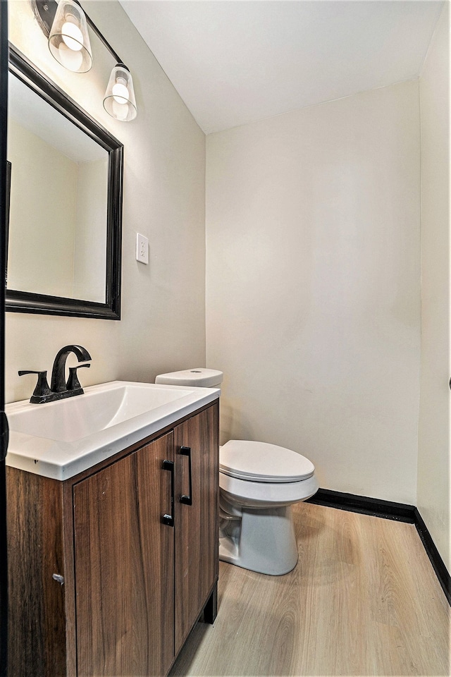 bathroom featuring wood-type flooring, toilet, and vanity