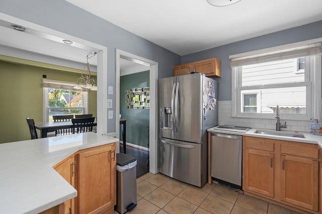 kitchen with light tile patterned flooring, appliances with stainless steel finishes, sink, backsplash, and a chandelier