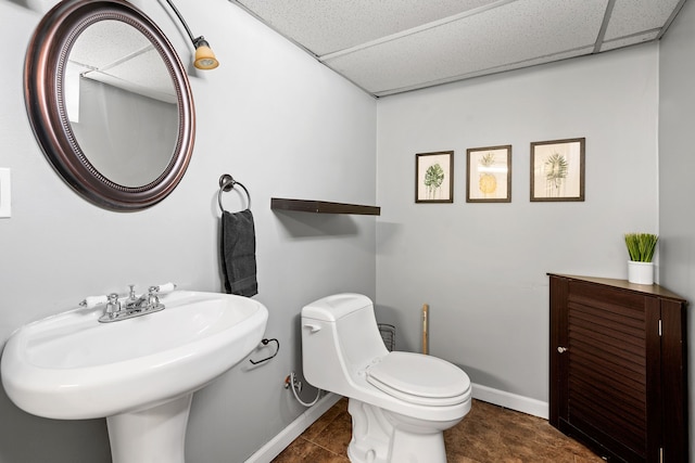 bathroom with sink, a drop ceiling, tile patterned floors, and toilet