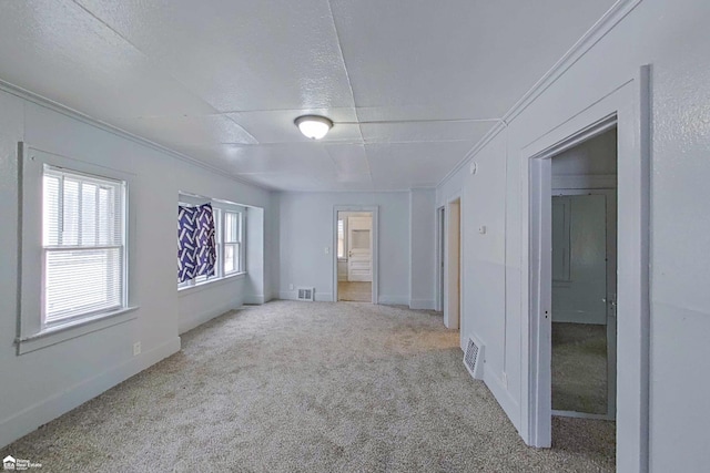 empty room with ornamental molding, light colored carpet, and a textured ceiling