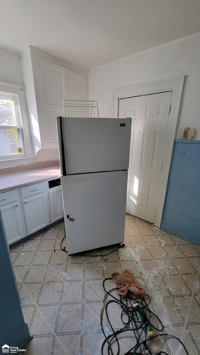 kitchen with white refrigerator and white cabinetry