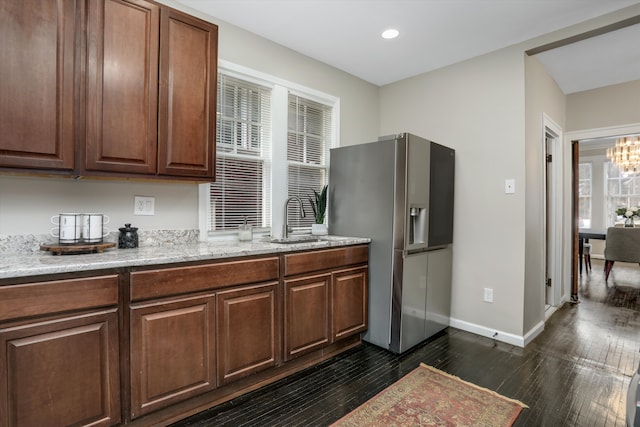 kitchen with sink, a chandelier, stainless steel fridge, dark hardwood / wood-style flooring, and light stone countertops