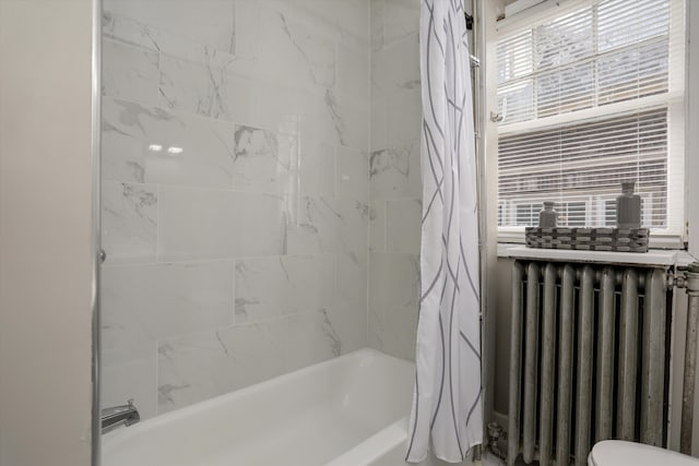 bathroom featuring radiator and shower / bath combination with curtain