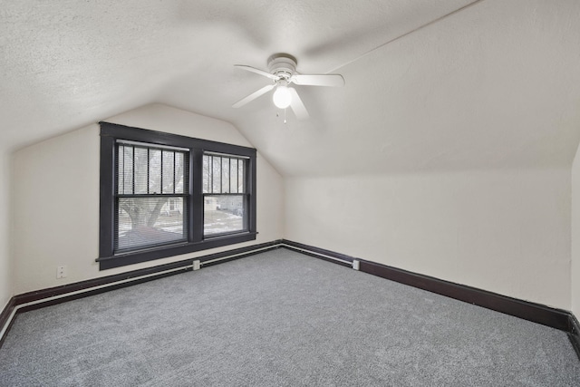 additional living space with ceiling fan, vaulted ceiling, a textured ceiling, and carpet