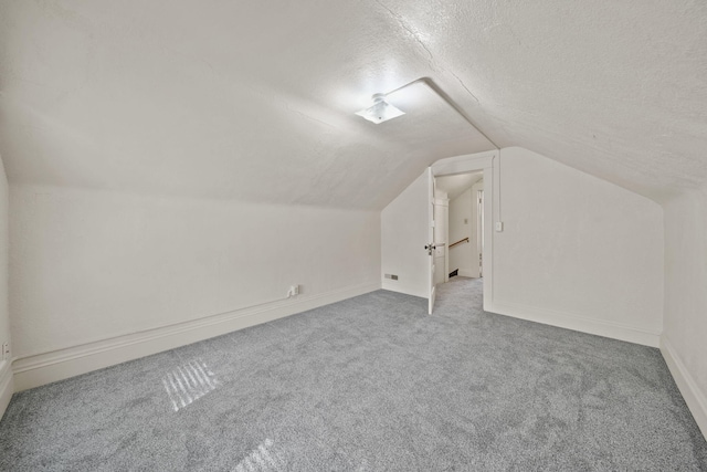 additional living space with vaulted ceiling, carpet flooring, and a textured ceiling