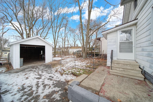 yard layered in snow featuring an outbuilding and a garage