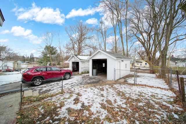 snow covered property with a garage and an outbuilding