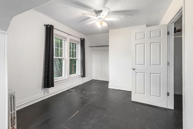 unfurnished bedroom with ceiling fan, radiator, and a closet