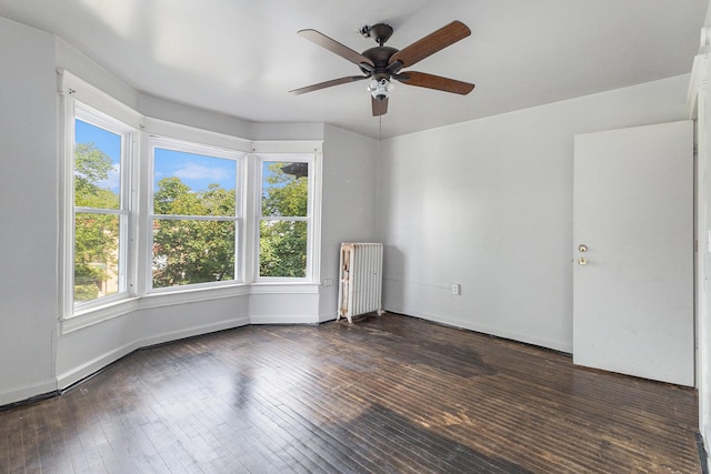 empty room featuring ceiling fan, radiator heating unit, and dark hardwood / wood-style flooring