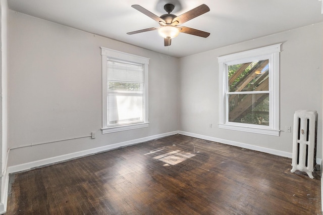 unfurnished room featuring plenty of natural light, dark hardwood / wood-style floors, and radiator heating unit