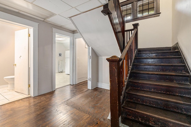 stairs with hardwood / wood-style flooring and a paneled ceiling