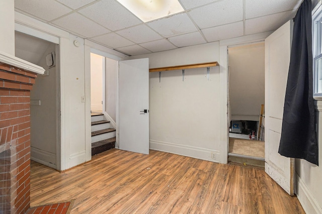 unfurnished bedroom featuring hardwood / wood-style floors, a drop ceiling, and a closet