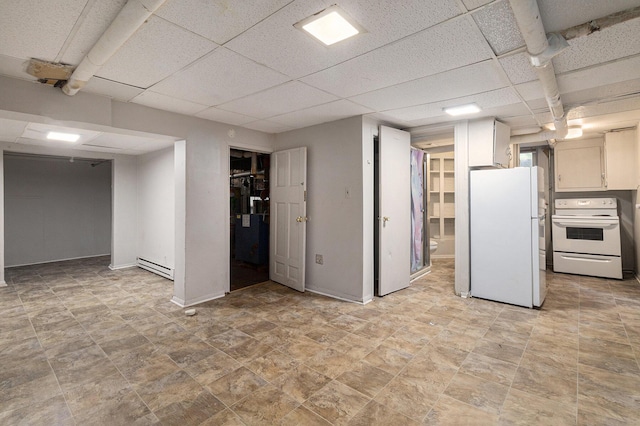 basement featuring white fridge, a drop ceiling, and baseboard heating