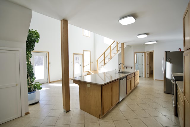 kitchen with stainless steel appliances, sink, a center island with sink, and light tile patterned floors