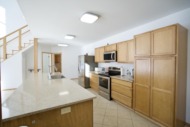 kitchen featuring light stone counters, an island with sink, appliances with stainless steel finishes, and sink