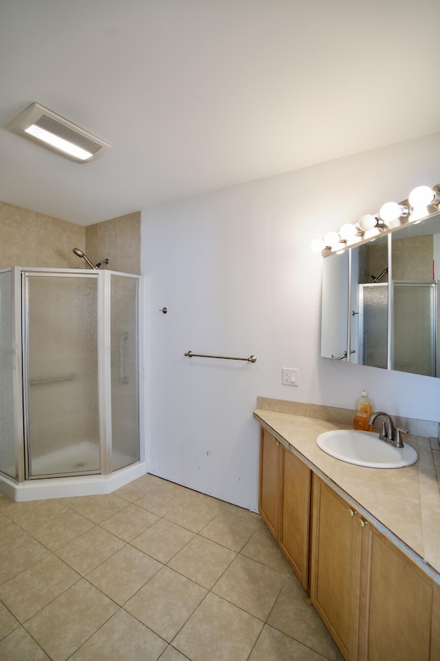 bathroom featuring vanity, a shower with shower door, and tile patterned flooring