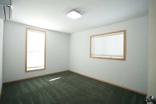 spare room featuring a wall unit AC and dark carpet