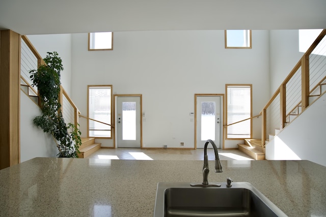 kitchen featuring a high ceiling, sink, and light stone counters