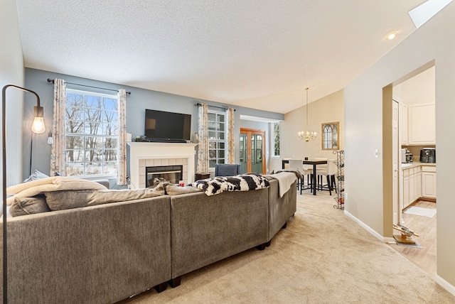 living room featuring a chandelier, vaulted ceiling, light carpet, a textured ceiling, and a tiled fireplace