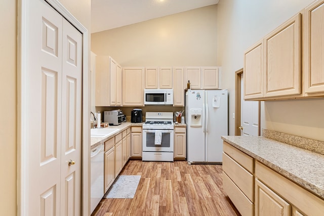 kitchen featuring white appliances, light brown cabinetry, sink, and light wood-type flooring