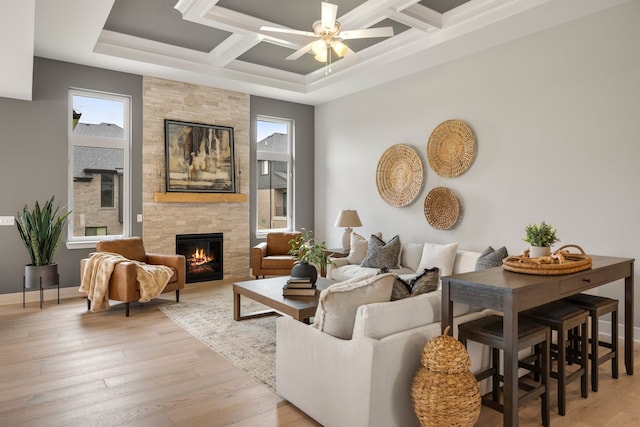 living room featuring coffered ceiling, light wood-type flooring, beamed ceiling, ceiling fan, and a fireplace