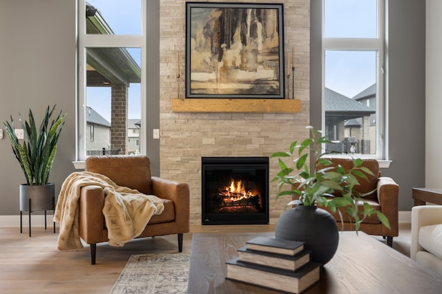 sitting room with a stone fireplace and light hardwood / wood-style flooring