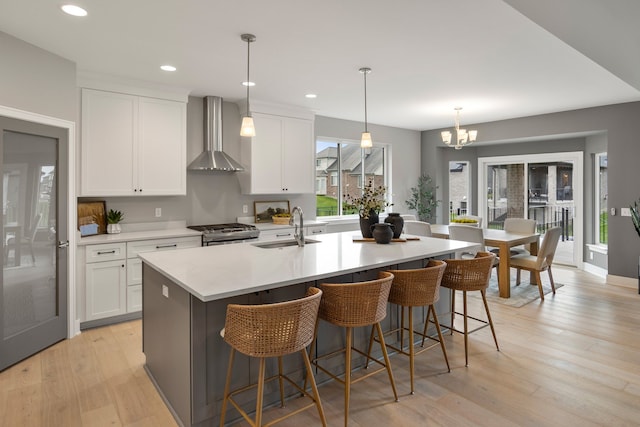 kitchen featuring sink, stainless steel gas range oven, white cabinets, and wall chimney exhaust hood