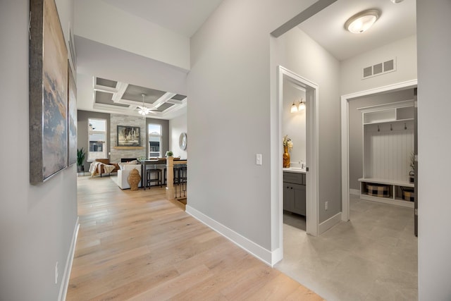 hallway with coffered ceiling and light hardwood / wood-style floors