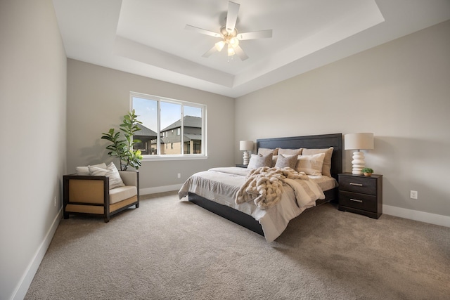 carpeted bedroom featuring ceiling fan and a raised ceiling