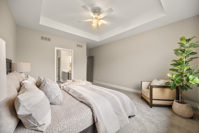 bedroom featuring ceiling fan, light colored carpet, connected bathroom, and a raised ceiling