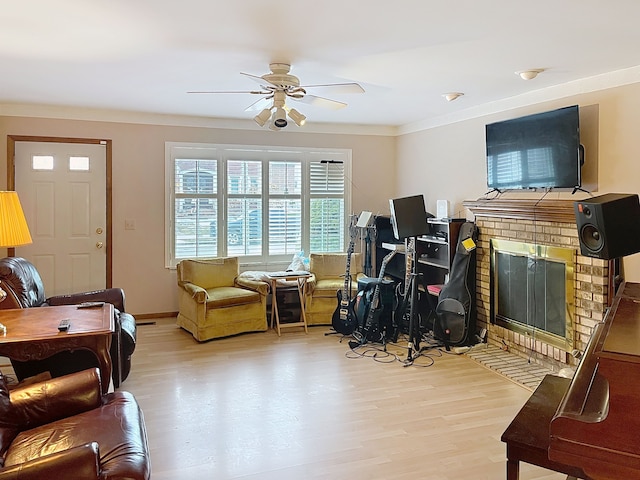 living room with light hardwood / wood-style flooring, crown molding, a fireplace, and ceiling fan