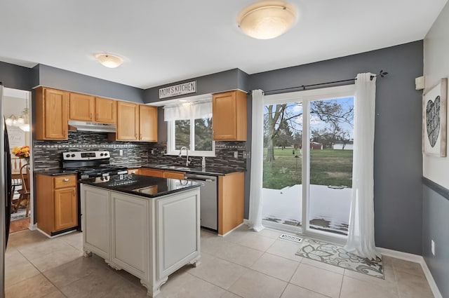 kitchen featuring sink, tasteful backsplash, a center island, light tile patterned floors, and stainless steel appliances