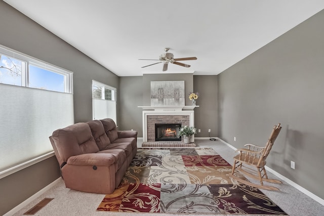 living room featuring a brick fireplace, light carpet, and ceiling fan