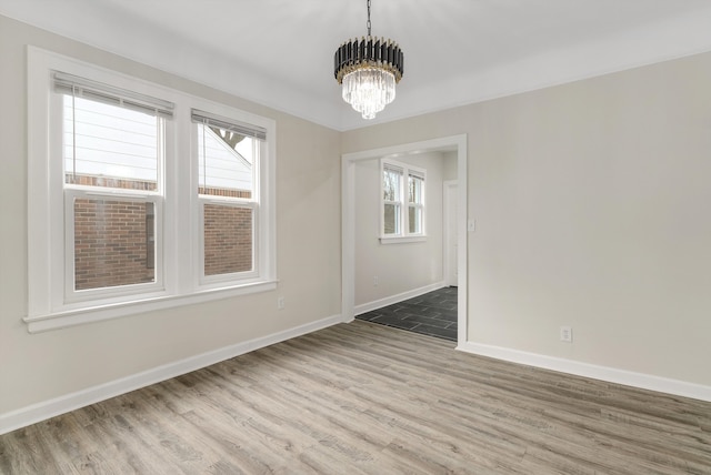 empty room featuring an inviting chandelier and wood-type flooring