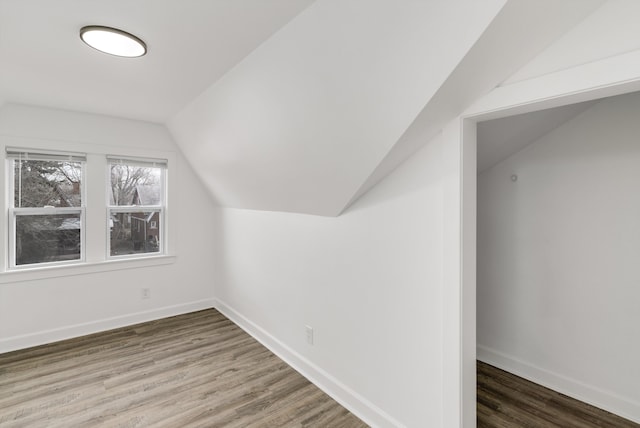 additional living space with dark wood-type flooring and vaulted ceiling