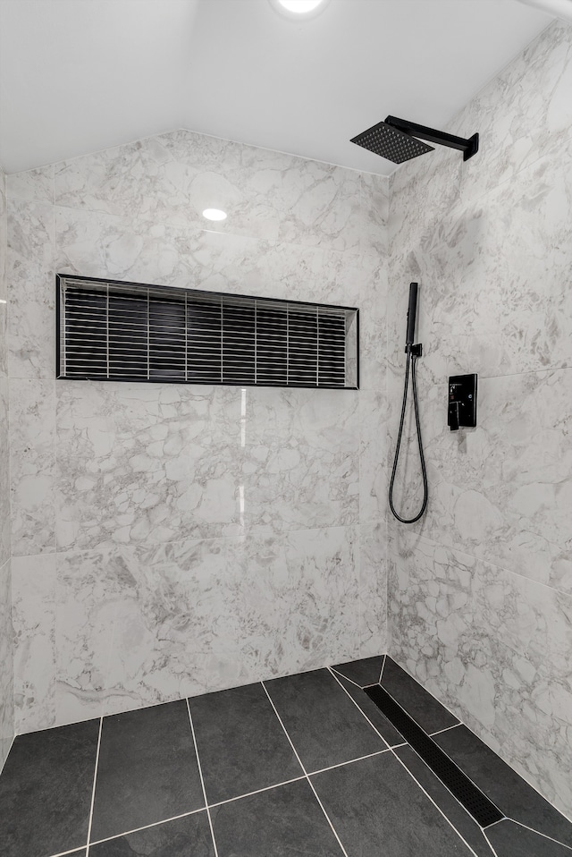 bathroom with tile patterned flooring, lofted ceiling, and a tile shower