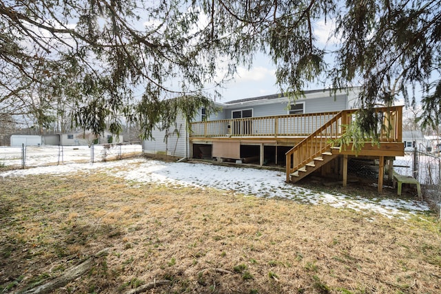 snow covered house featuring a deck and a lawn