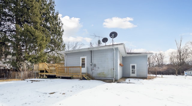 snow covered back of property featuring a wooden deck