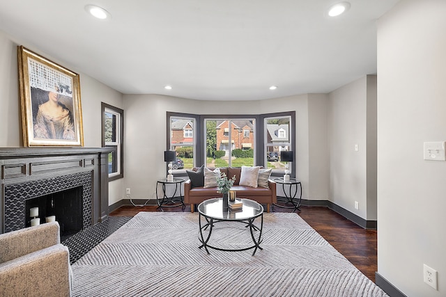 living area with a tile fireplace and dark wood-type flooring