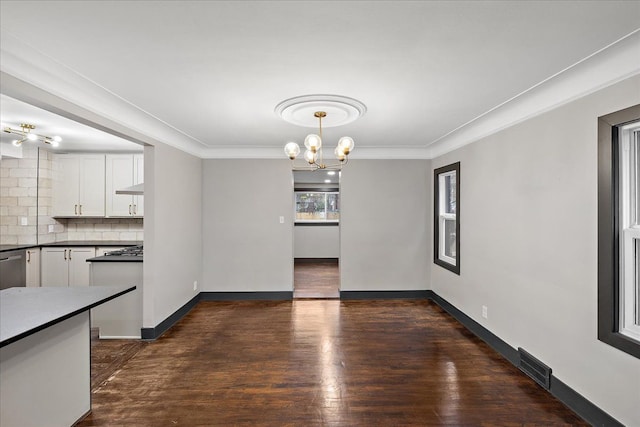 unfurnished dining area featuring an inviting chandelier, ornamental molding, and dark hardwood / wood-style floors