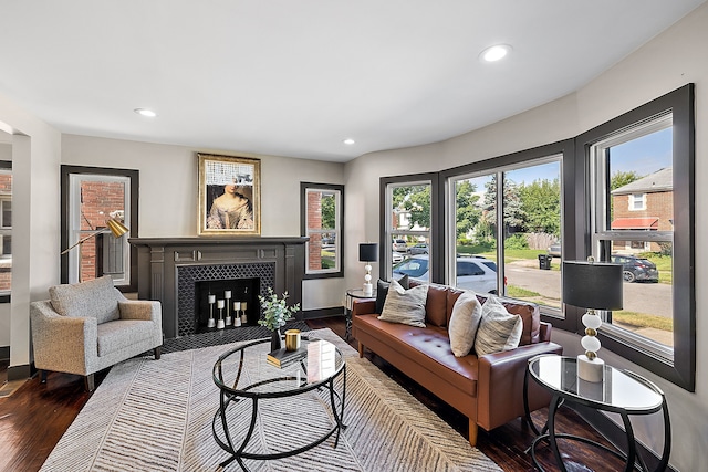 living room with a wealth of natural light, a tile fireplace, and dark hardwood / wood-style floors