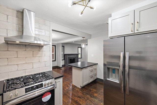 kitchen with appliances with stainless steel finishes, decorative light fixtures, white cabinets, dark hardwood / wood-style flooring, and wall chimney exhaust hood