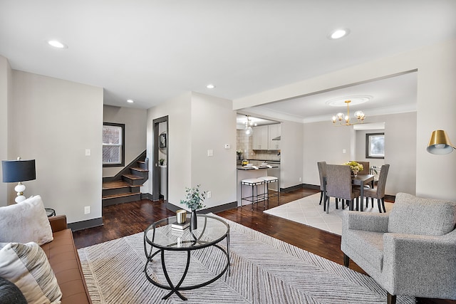 living room with crown molding, dark wood-type flooring, and an inviting chandelier